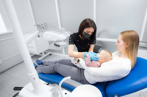 Dentist examining baby held by mother