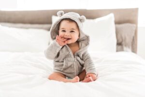 Happy, smiling baby sitting on bed