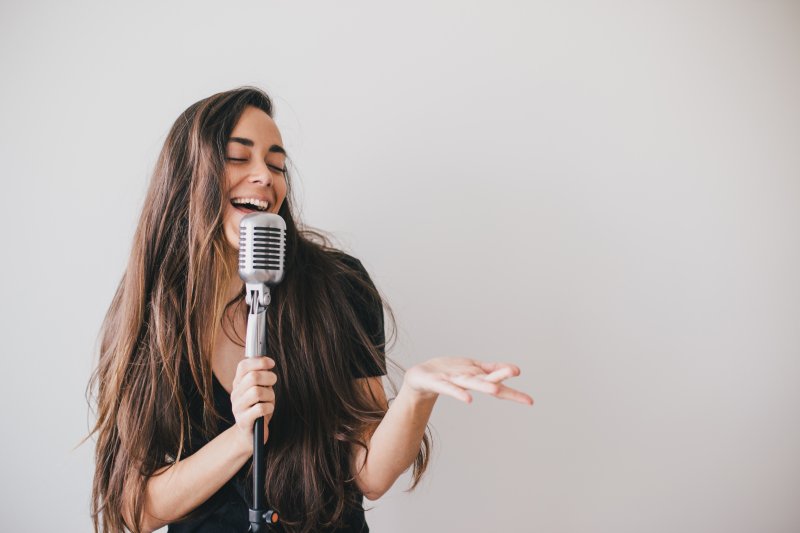 a woman smiling and singing with a microphone